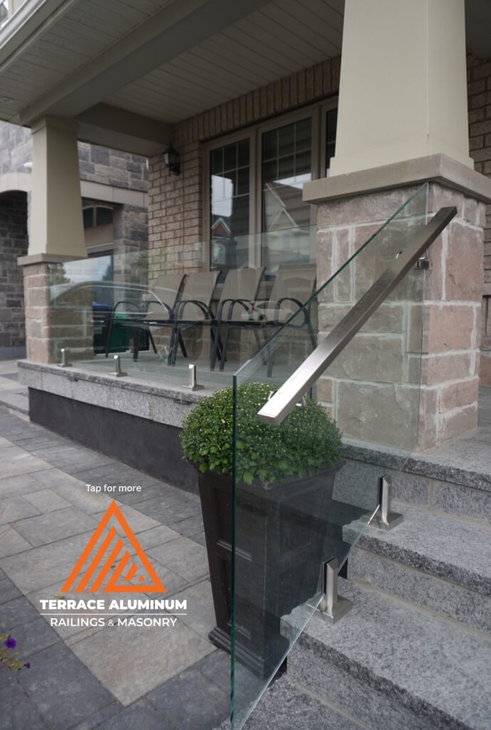 Frameless glass railing on a new flagstone porch in Toronto with brushed nickel hardware and rectangular handrail